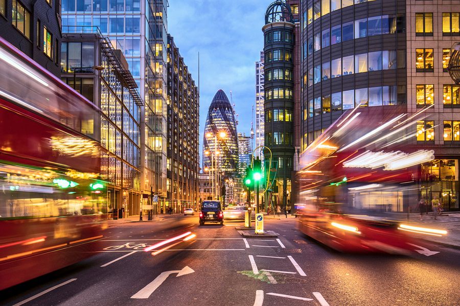 En bild av Gurkan (30 St Mary Axe) tagen med kort slutartid i London nattetid, medan två Londonbussar kör förbi.
