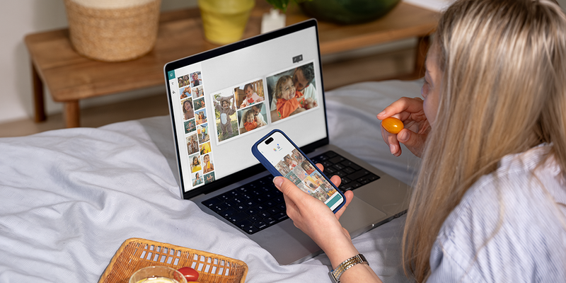 En kvinna använder önskefotos desktop editor på sin laptop medan hon äter en körsbärstomat för att skapa en personlig fotobok, som inspiration till en enkel fotobok och en fotoalbum maker.