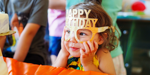 En flicka med roliga Happy Birthday-glasögon, som letar efter en födelsedagspresent eller personlig födelsedagspresent från önskefoto.