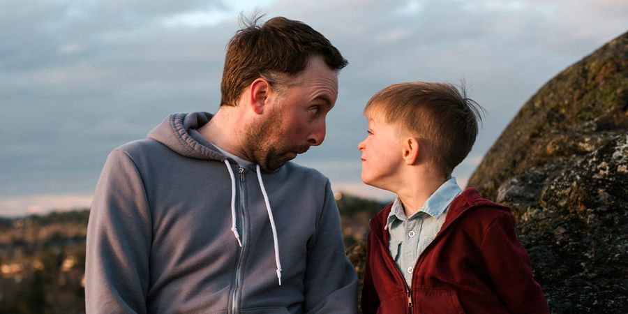 Far och son gör roliga miner. En rolig önskefoto presentidé till fars dag för en busig pappa.