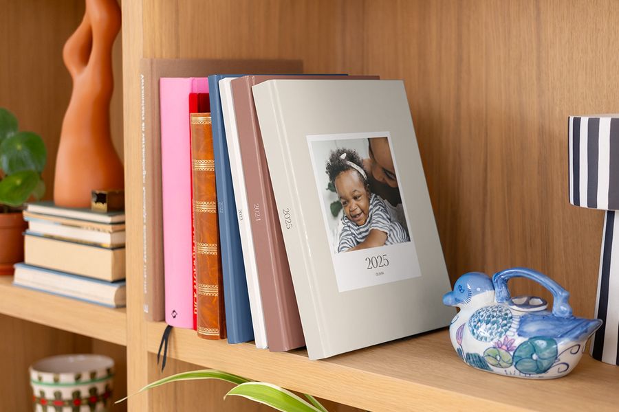 En rad färgglada, mönstrade årsböcker från Önskefoto snyggt uppställda i en bokhylla.