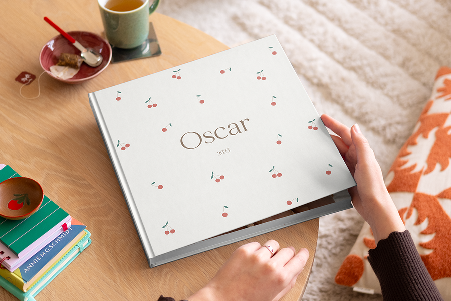 En kvinna som ska öppna en fotobok till bebis från önskefoto på ett soffbord i trä.