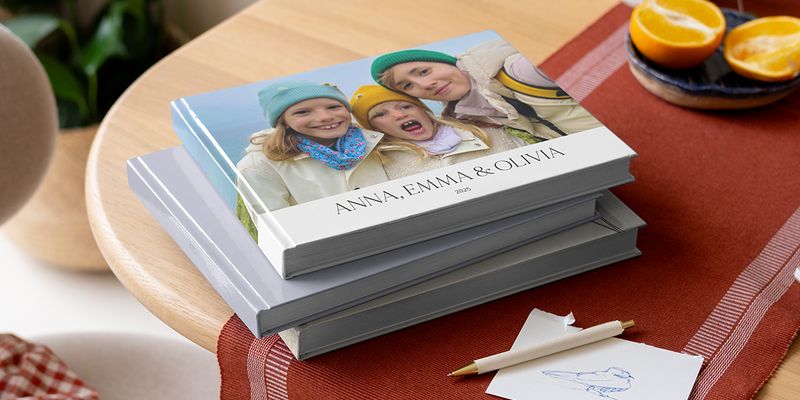 Ett urval av fotoböcker från önskefoto på ett bord med en penna, som visar syskon på omslaget som inspiration för svenska citat och texter till bilder.