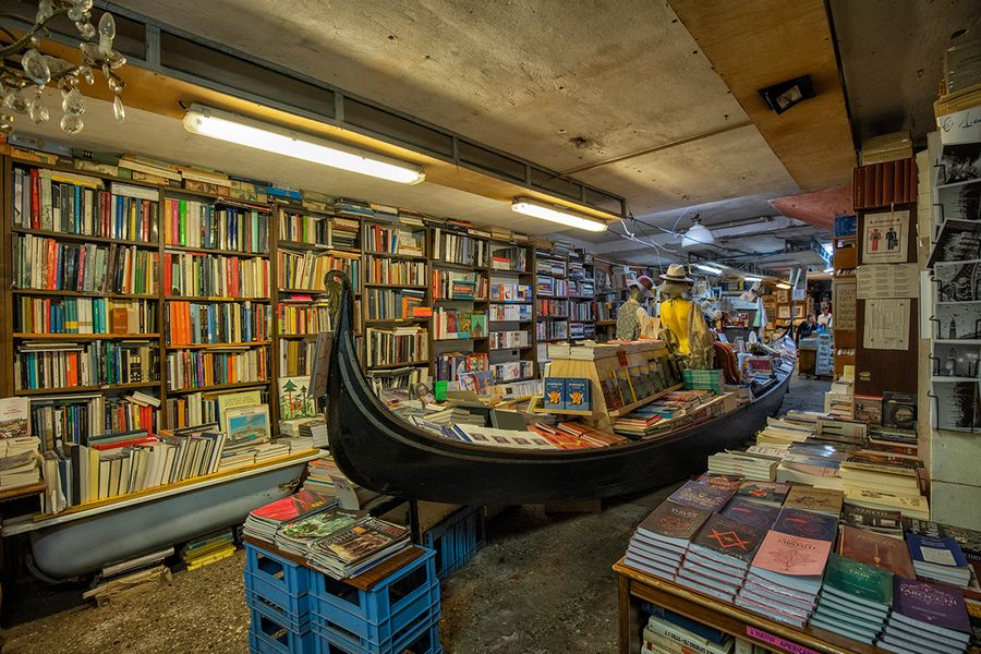 Libreria Acqua Alta i Venedig, Italien, med böcker som förvaras i en gondol och badkar för att skyddas mot vattenet, ett unikt tips för en litterär resa med önskefoto.