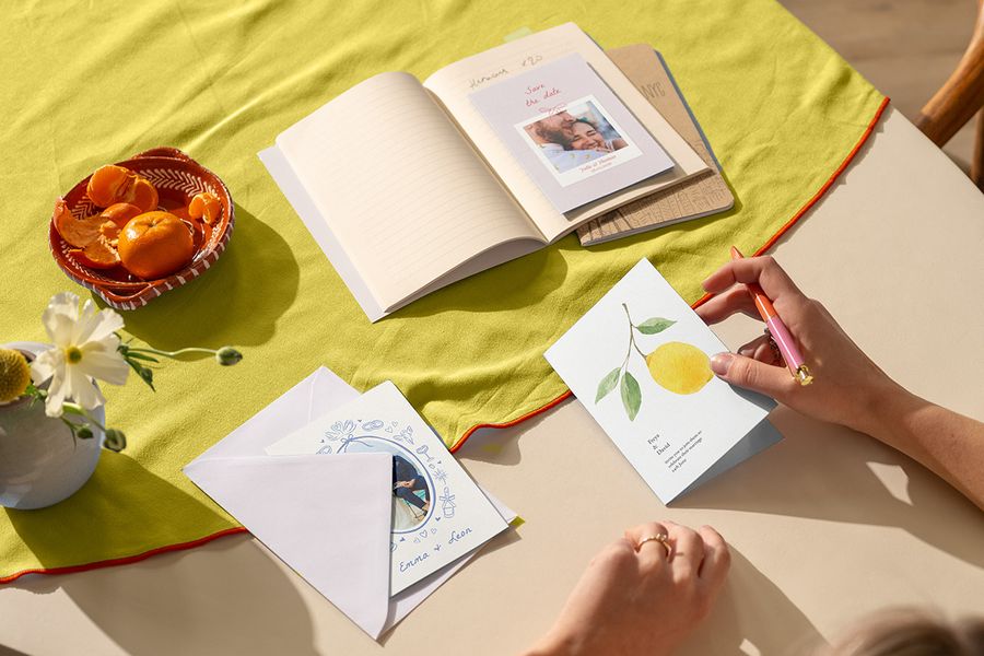 Personliga bröllopsinbjudningar på en färgstark bordsduk i citrustoner, vilket illustrerar bröllopstrender 2026 och färgtema för bröllop hos önskefoto.