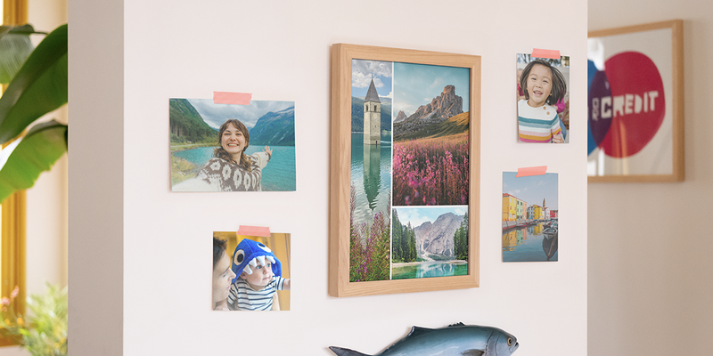 önskefoto framkalla bilder på en vägg i hemmet, med en stor ram fylld med landskapsbilder och fyra individuella familjebilder på väggen, som inspiration till fotoframkallning och att beställa foton online.