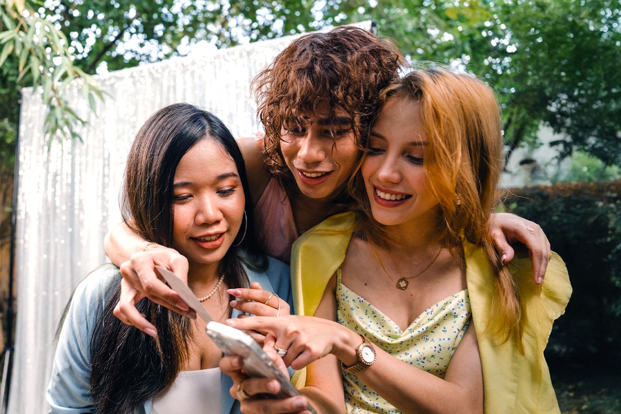 Tre vänner i festkläder på ett bröllop deltar i en fotojakt, som inspiration till önskefoto bröllopslekar och roliga bröllopslekar för gäster.