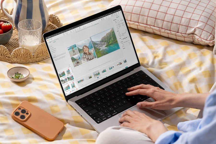 Någon använder önskefotos fotobokseditor på en laptop i sängen, som inspiration till en enkel fotobok och en fotoalbum maker.