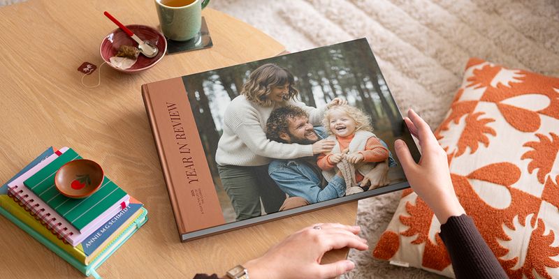 En önskefoto coffee table photo book med en year in review-framsida och ett fint familjefoto på omslaget, placerad på ett soffbord som inspiration till en personlig coffee table book.