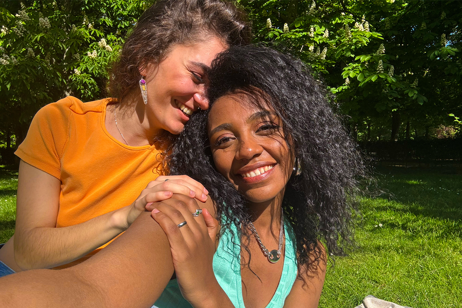 Två kvinnor ler och tar en selfie i en grönskande park, och visar hur starka färger kan göra bilder i solljus mer levande och fulla av liv.