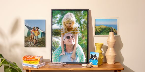 Ett urval önskefoto fotoprintar visade i hemmet, med en hundbild på ett sidobord, en poster med barn på väggen och två inramade foton, som inspiration till foton på väggen och vårfräsch heminredning.