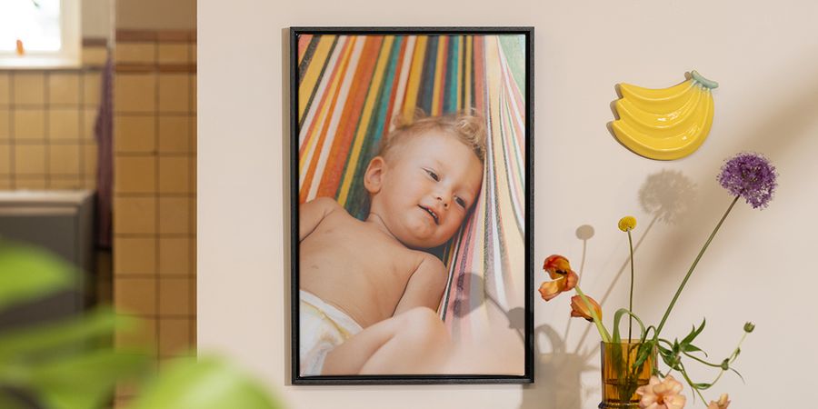 Personlig önskefoto väggkonst med ett foto av en baby bredvid blommor och fruktdekoration, som inspiration till sommardekoration i hemmet.