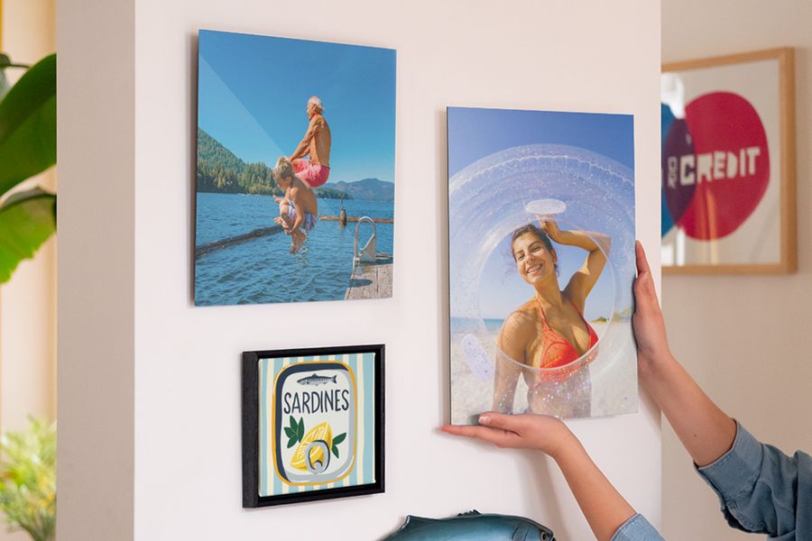 En bildvägg med personlig önskefoto väggkonst visar en leende kvinna på stranden, en man och en pojke som hoppar i havet samt en illustration av en sardinkonserv, som inspiration till sommardekoration och somrig väggdekor.