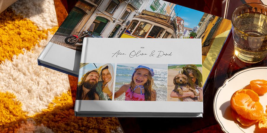 Två olika önskefoto resefotoböcker visas tillsammans, bland annat en liggande fotobok resa med familjens resebilder på omslaget och en annan med en semesterbild av en spårvagn, som inspiration till olika typer av fotoalbum travel.