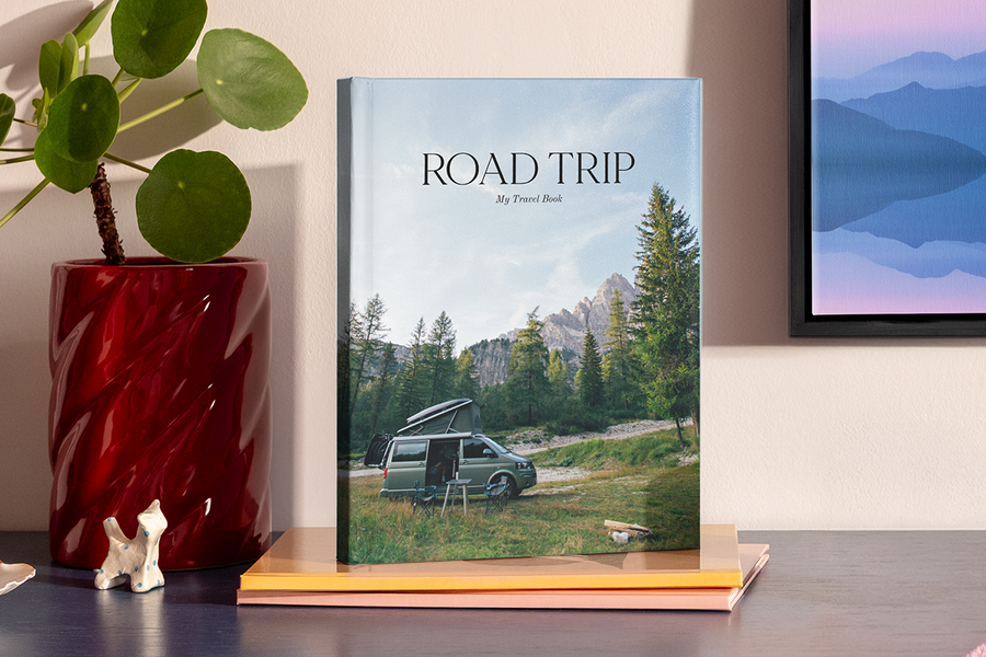 En stor stående fotobok visar en bild av en husbil i ett bergslandskap som liknar en nationalpark, som illustrerar önskefotos fotobok titel idéer för bilsemester.