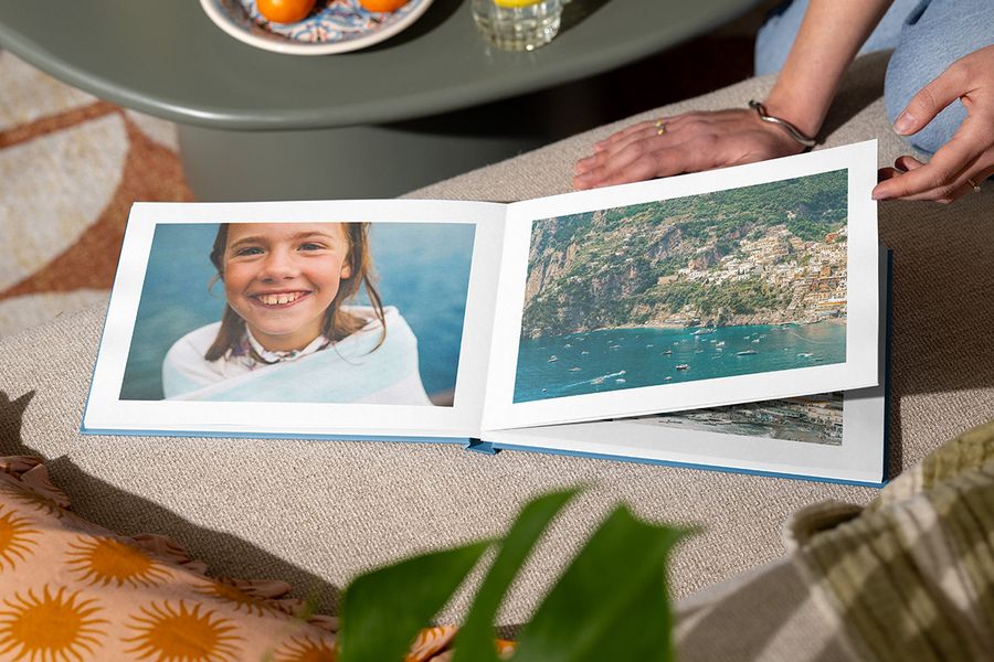 En öppen fotobok visar en flicka som ler vid havet på en sida och ett strandlandskap på den andra, vilket illustrerar önskefotos Holiday Escape-design med fängslande helsidesfotografier.