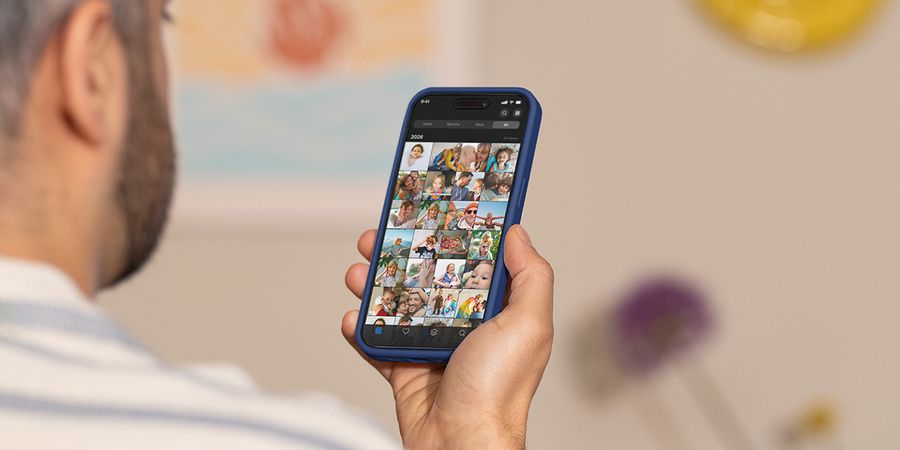 En man håller upp telefonen och bläddrar genom sin kamerarulle, vilket illustrerar önskefotos guide till att hantera fotoöverbelastning och sortera bilder.