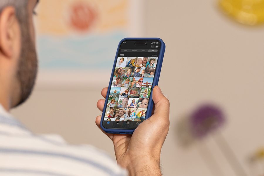 En man håller upp telefonen och bläddrar genom sin kamerarulle, vilket illustrerar önskefotos guide till de bästa verktygen för att organisera bilder.