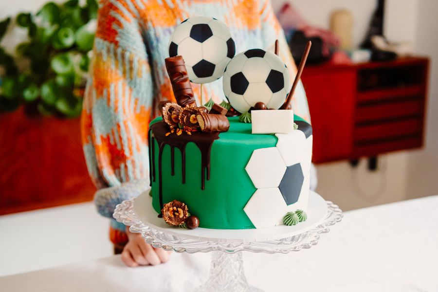 En barnfödelsedagstårta dekorerad med fotbollar och chokladbitar, vilket illustrerar önskefotos tips om att fotografera stjärntårtan innan gästerna anländer.
