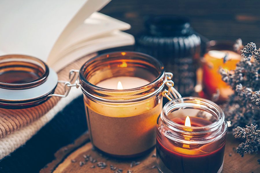 Ett par tända ljus står bredvid en blomkvist, vilket illustrerar hur ljus bidrar till en mysig höststämning i önskefotos tips för hygge-inredning.