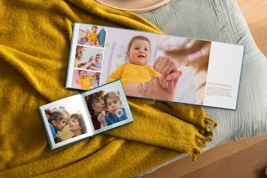 Två personliga fotoböcker ligger uppslagna med familjebilder, vilande på en senapsgul pläd, vilket illustrerar hur önskefotos fotoböcker passar in i ett hygge-hem.