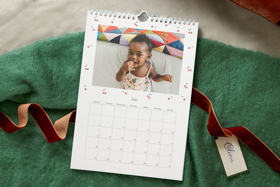 Personlig fotokalender med en bild på en bebis i en sommarklänning, som illustrerar önskefotos idéer för att skapa en personlig kalender till bebisens första jul.
