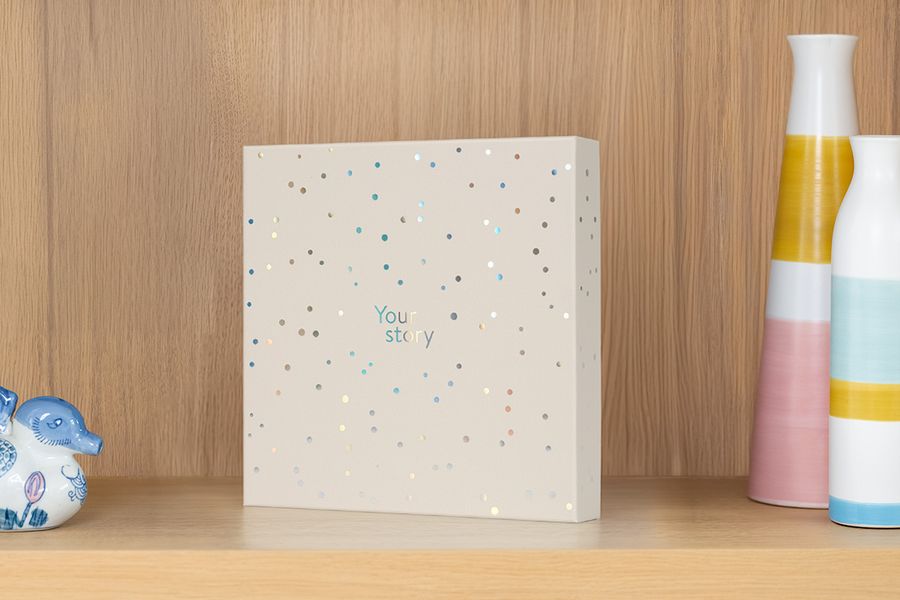 Presentationsboxen står på en hylla bredvid en vas och prydnadssaker, vilket illustrerar hur den också fungerar som en attraktiv förvaringsbox för fotoalbum.