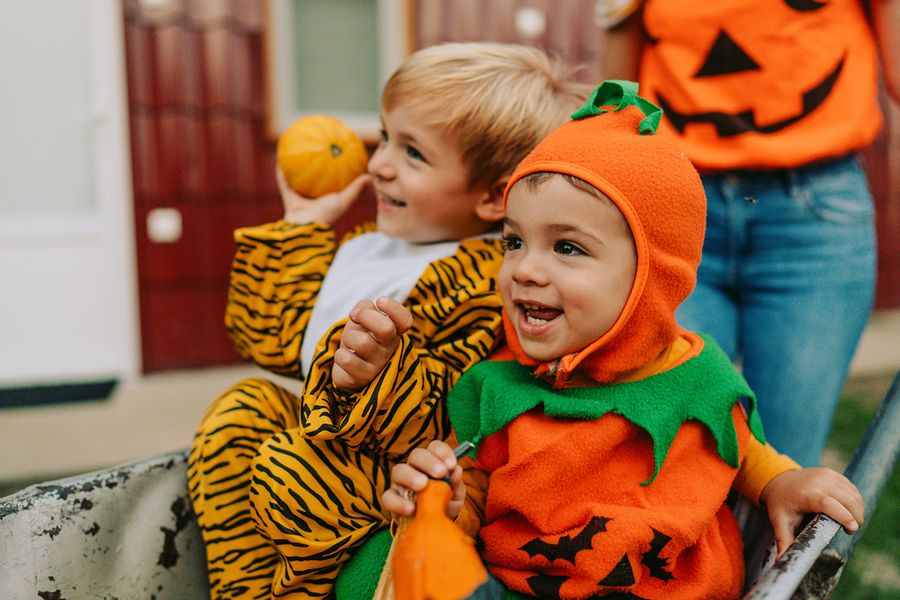 Två barn i Halloween-kostymer, ett utklätt till pumpa och ett till tiger, vilket illustrerar önskefotos gulliga Halloween-citat för Instagram.