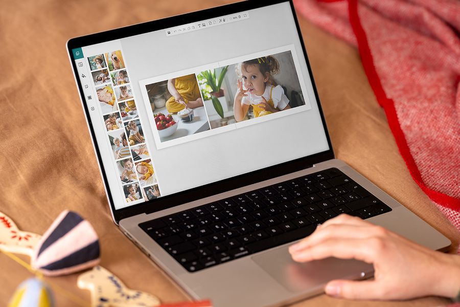 Händer vid en laptop som visar önskefotos onlineeditor, för att visa hur enkelt det är att skapa en fotobok som personlig julklapp, som illustrerar önskefotos tidsplan för att skapa en personlig fotopresent.