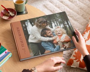 En önskefoto coffee table photo book med en year in review-framsida och ett fint familjefoto på omslaget, placerad på ett soffbord som inspiration till en personlig coffee table book.