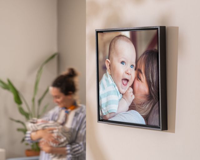 Inramad canvastavla med en mamma som myser med sin bebis, upphängd på väggen
