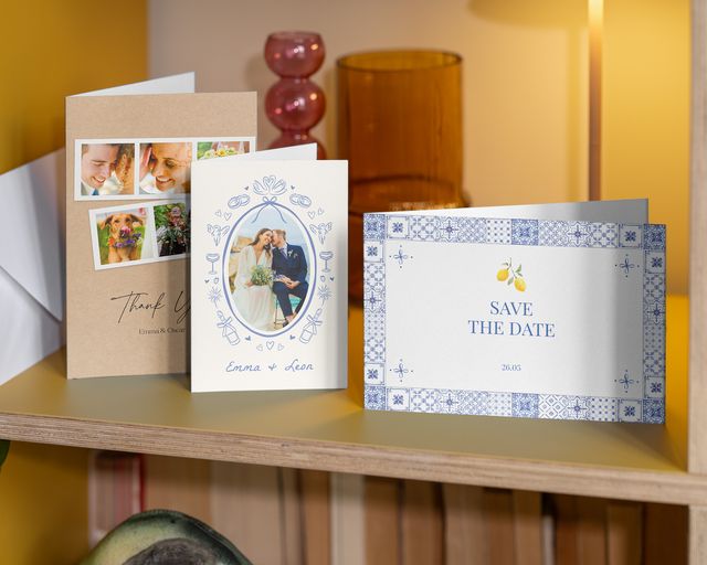 Tre bröllopsfotokort på en hylla: ett save-the-date-kort och två tackkort.